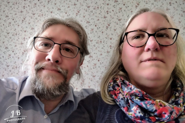 Martina und Jörg Bollhöfer lächeln in die Kamera. Das Foto zeigt sie nebeneinander sitzend, seit 30 Jahren verheiratet.