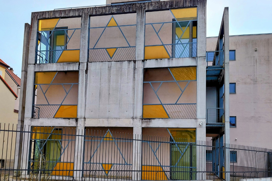 Gebäide mit geometrischen Formen und gelben Glasscheiben, stilisiert der Davidsstern, die Synagoge des Ortes